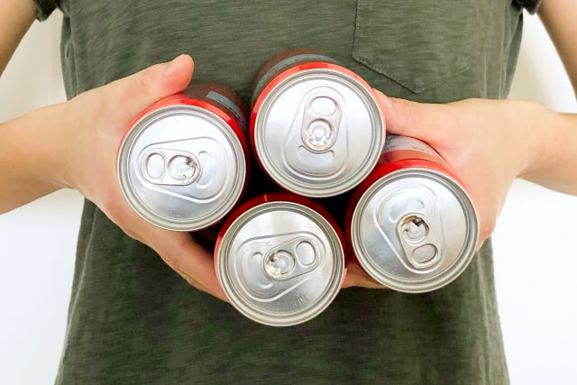 缶ジュースを4本持っている画像