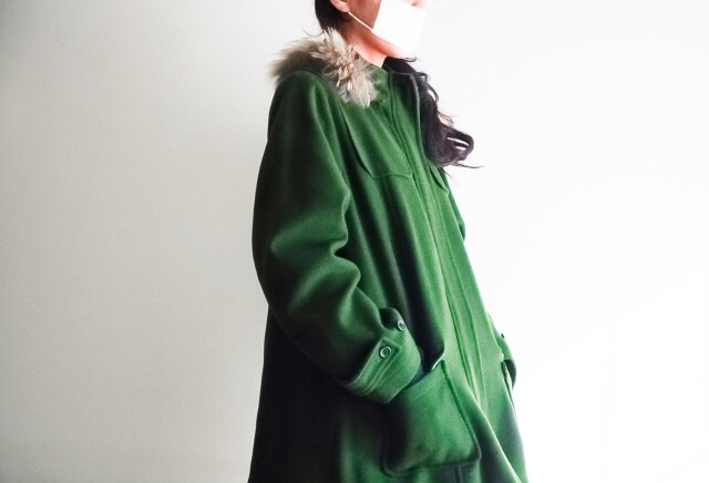 ポケットに手を入れている緑のコートを着た女性の画像