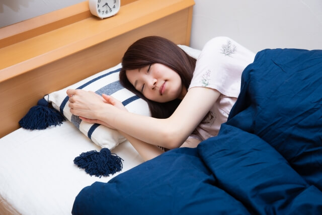 ベッドで気持ちよさそうに寝ている女性の画像