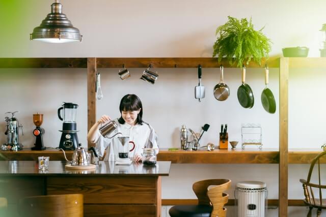 キッチンでコーヒーを入れている女性の画像