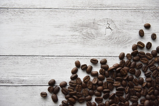 グレーの板の上に散らばっているコーヒー豆の画像