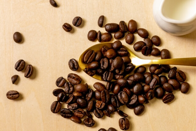 コーヒー豆を金色のスプーンですくっている画像