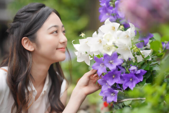 白と紫のお花の匂いを嗅いでいる女性の画像
