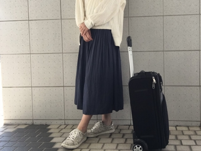 スーツケースの横で立っている女性の画像