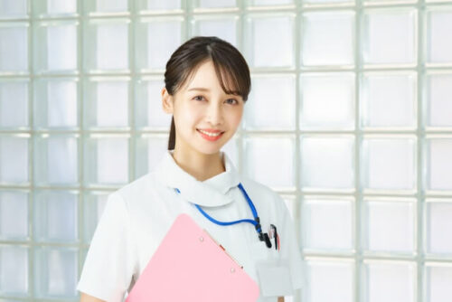 ピンクのファイルを抱えて笑顔の看護師画像